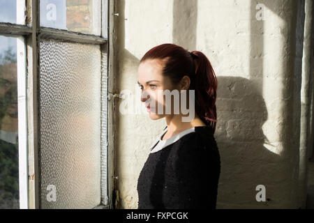 Ernste Frau, Blick aus dem Fenster Stockfoto