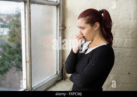 Frau, die weinend am Fenster Stockfoto