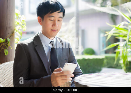 Junge asiatische Geschäftsmann mit Telefon in der outdoor-Szene Stockfoto