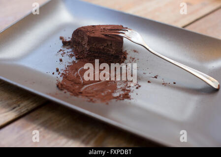 Herz, gezeichnet in Kakaopulver und die Hälfte gegessen Schokoladenkuchen Stockfoto