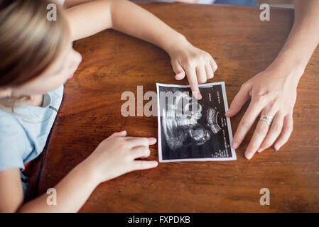 Mädchen, die Ultraschall-Foto von ihr neues Geschwisterchen zu betrachten Stockfoto