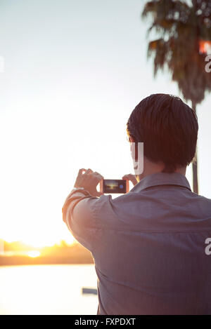 Mann fotografiert Sonnenuntergang mit smartphone Stockfoto