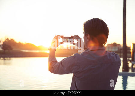 Mann fotografiert Sonnenuntergang mit smartphone Stockfoto