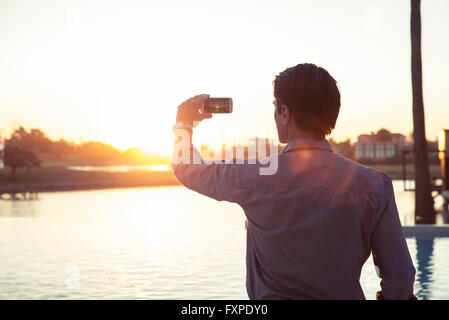 Mann fotografiert Sonnenuntergang mit smartphone Stockfoto