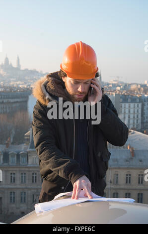 Bauleiter reden über Handy und Blaupausen betrachten Stockfoto