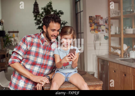 Vater und Tochter gemeinsam Smartphone betrachten Stockfoto