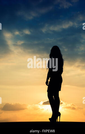 Voller Länge Silhouette einer Frau gegen einen dramatischen Sonnenuntergang