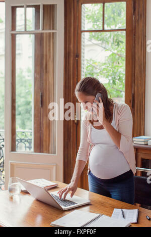 Frau mit Laptop-Computer und Anruf tätigen Stockfoto