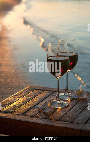 Romantischen Strand-Szene: zwei Gläser Rotwein bei Sonnenuntergang in der Nähe von Wasser Stockfoto