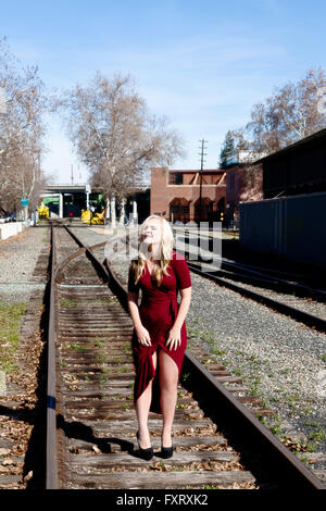 Blonde Frau im roten Kleid auf Rail Road Tracks stehen Stockfoto