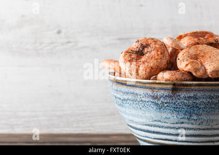 Orange Speisepilze - Safran-Milch-Cap in Keramikschale auf Holztisch mit Textfreiraum. Extreme Nahaufnahme. Stockfoto