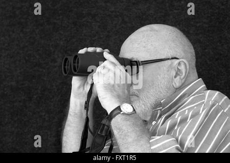 Eine alte Glatzkopf Blick durch ein Fernglas. Stockfoto