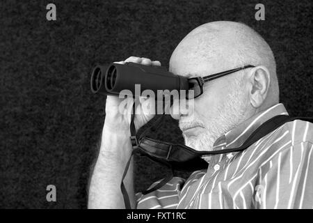 Eine alte Glatzkopf Blick durch ein Fernglas. Stockfoto