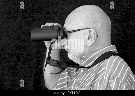 Eine alte Glatzkopf Blick durch ein Fernglas. Stockfoto