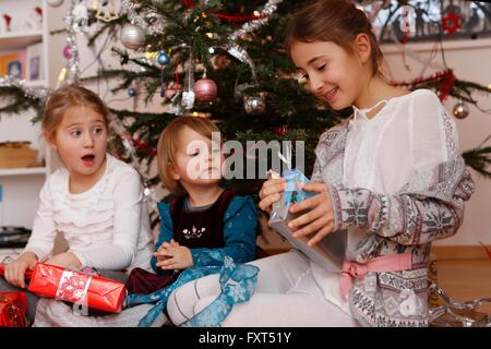 Mädchen vor Weihnachtsbaum Geschenke öffnen Stockfoto