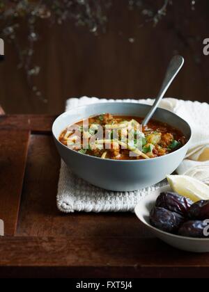 Harira Suppe in Schüssel mit Datteln und Zitronenscheibe Stockfoto