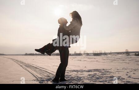 Junger Mann mit Frau auf schneebedeckten Feld Stockfoto