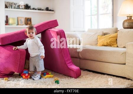Baby Junge spielt im Fort aus Sofakissen hergestellt Stockfoto