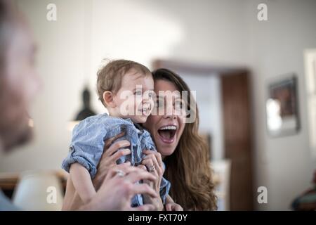 Mutter hält lächelnden jungen, offenen Mund vor Überraschung Stockfoto