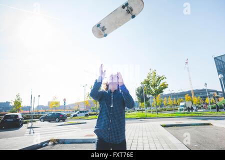 Junge männliche urban Skater Skateboard Mitte Luft werfen Stockfoto