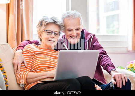 Älteres Paar auf Sofa im Wohnzimmer Blick auf laptop Stockfoto