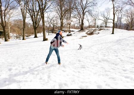Junger Mann mit Hund im verschneiten Central Park, New York, USA Stockfoto