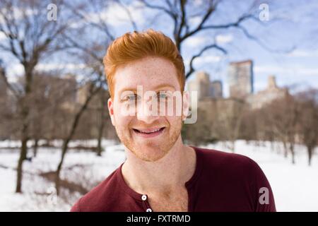 Porträt von roten Haaren junger Mann im verschneiten Central Park, New York, USA Stockfoto