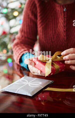 Nahaufnahme eines Womans Hände wickeln Weihnachtsgeschenk am Tisch Stockfoto