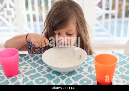 Mädchen essen Frühstück aus Schale mit Löffel Stockfoto