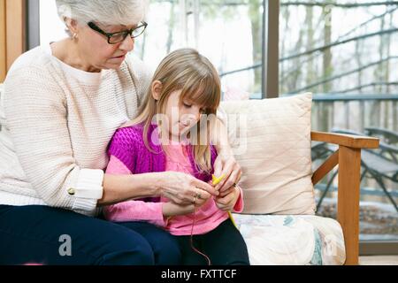 Ältere Frau und Enkelin stricken auf Sofa im Wohnzimmer Stockfoto