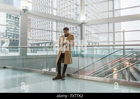 Junger Geschäftsmann Auswahl Smartphone Musik im Zug Bahnhof atrium Stockfoto