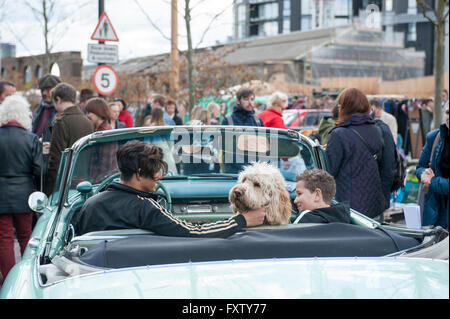 Zwei Kinder sitzen in einem klassischen Auto mit ihrem Hund, posieren für Menschen am Classic Car Boot Sale Cubitt Square, Kings Cross Stockfoto