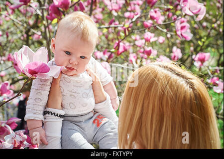 Mutter halten Baby im blühenden Magnolien-Garten Stockfoto