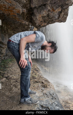 Mann Headbanging unter dem Gewässer-Wasserfall Stockfoto
