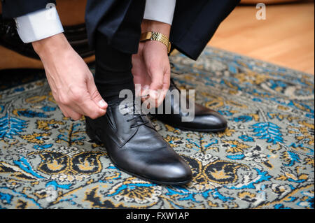 Bräutigam fesselt die Schnürsenkel auf schwarze Hochzeitsschuhe Stockfoto