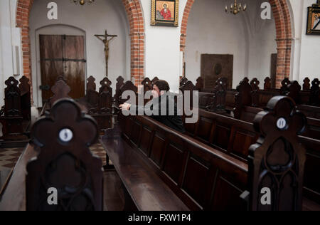 Mann kniet in kirchlichen Kirchenbank im Hauptschiff der Gdansk Oliwa erzkathedralen Basilika der Heiligen Dreifaltigkeit, der Jungfrau Maria zu beten... Stockfoto