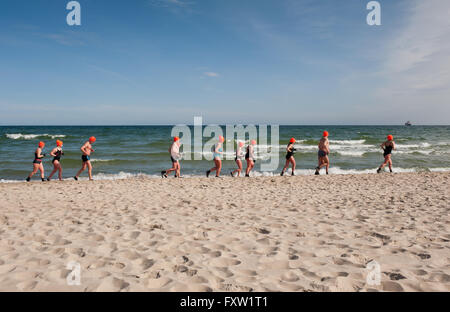 Winter-Schwimmer, die entlang des Strandes in Wladyslawowo Meeresküste, Polen, Europa, Menschen beim aktiven Sport im Meer Aufwärmen Stockfoto