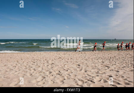 Winter-Schwimmer Aufwärmen entlang des Strandes in Wladyslawowo Meeresküste, Polen, Europa, Menschen beim aktiven Sport im Meer Stockfoto