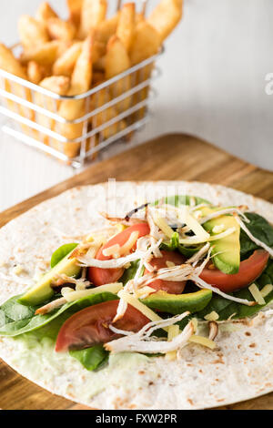 Gegrilltes Hühnerfleisch wraps mit Karotte, Käse, Avocado und Spinat. Mit Pommes Frites auf der Seite. Stockfoto