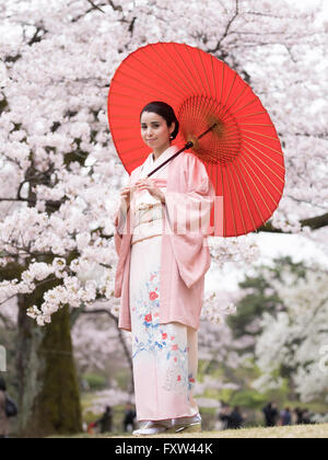 Porträt der jungen Japanerin tragen Kimono mit Kirschblüten in Shinjuku Gyōen Park, Tokio, Japan, Stockfoto