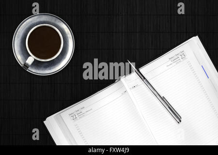 Kalender und Silber Stift auf schwarzen Schreibtisch mit Kaffee in Metall-Becher Stockfoto