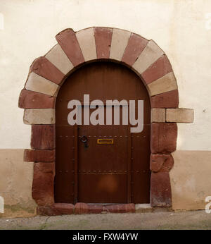 Alte Holztür mit einem großen Steinbogen, in einer alten Fassade Stockfoto