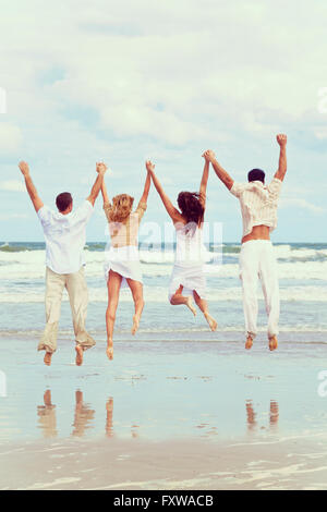Instagram Foto von vier Jugendlichen Stil zwei Paare Hand in Hand, Spaß springen glücklich feiern am Strand Stockfoto