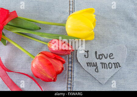 Ich liebe meine Mutter geschrieben am Denim Herzen dekoriert mit frischen Blumen Stockfoto