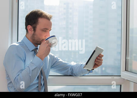 Geschäftsmann, trinken Kaffee und Blick auf digitale Tablet-Gerät Stockfoto