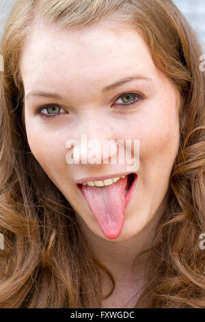 Junge Frau, die Zunge heraus Stockfoto