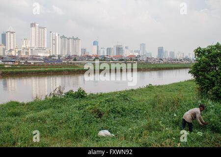 Jakarta, Indonesien. 18. April 2016. Ein Mann übernimmt den Rasen wie Hochhäuser auf dem Hintergrund gesehen werden. © Garry Andrew Lotulung/Pacific Press/Alamy Live-Nachrichten Stockfoto