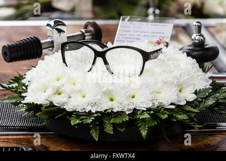 Shirley, Croydon, UK. 18. April 2016. Ein paar Gläser ruhen auf Blumen in einem Leichenwagen tragen den Sarg von Ronnie Corbett an Ronnie Corbetts Trauerfeier am St John die Evangelist-Kirche in Shirley, Croydon, Surrey. "Die zwei Ronnies" Star starb am 31. März 2016 mit einer vermuteten Bewegungsneuronkrankheit. Bildnachweis: London Pix/Alamy Live News Stockfoto