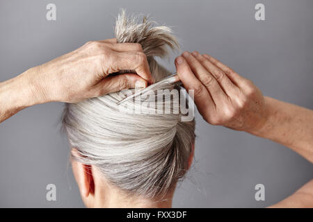 Rückansicht des Frau Styling graues Haar in Brötchen Stockfoto