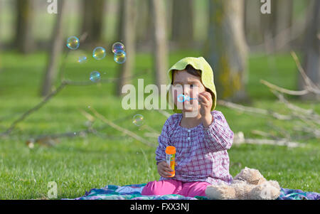 kleines Mädchen bläst ein Seifenblasen im Wald Stockfoto